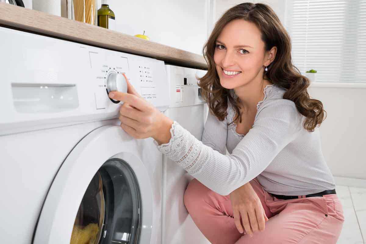 woman pressing button on washing machine
